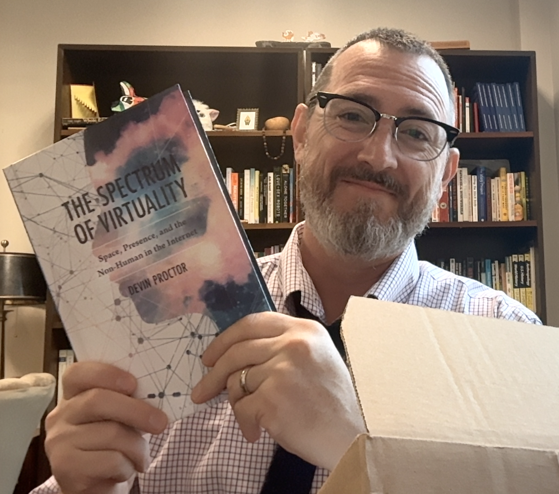 A man with glasses holds up a copy of "The Spectrum of Virtuality."